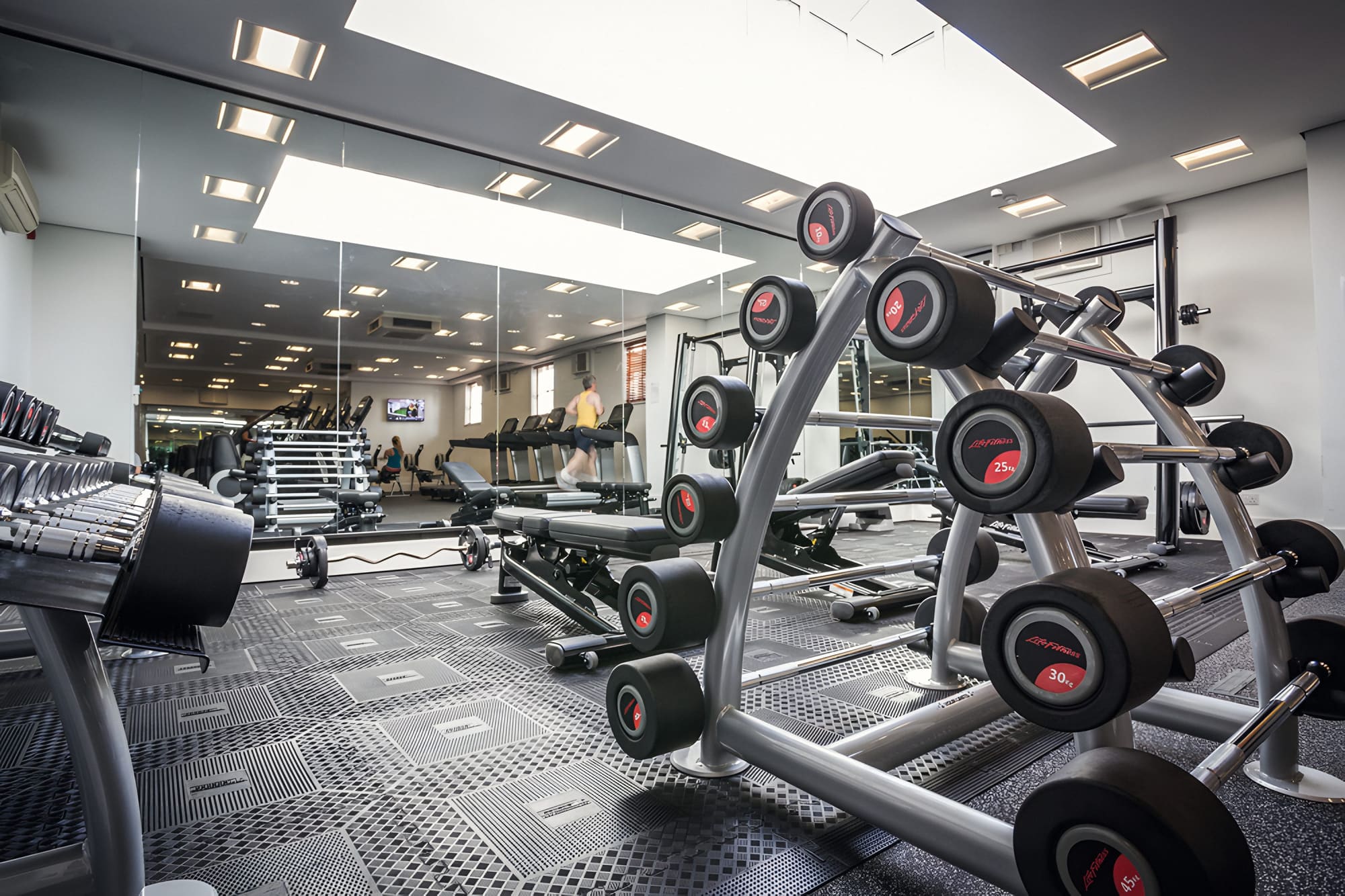 The gym floor at the Health & Fitness Club, Bedford Lodge Hotel: dumbbell racks, benches and a long skylight